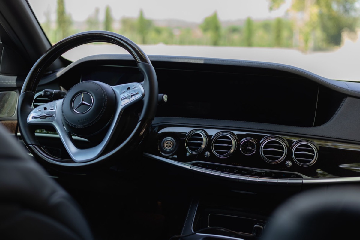 Intérieur luxueux d'une voiture avec volant en cuir et tableau de bord numérique.