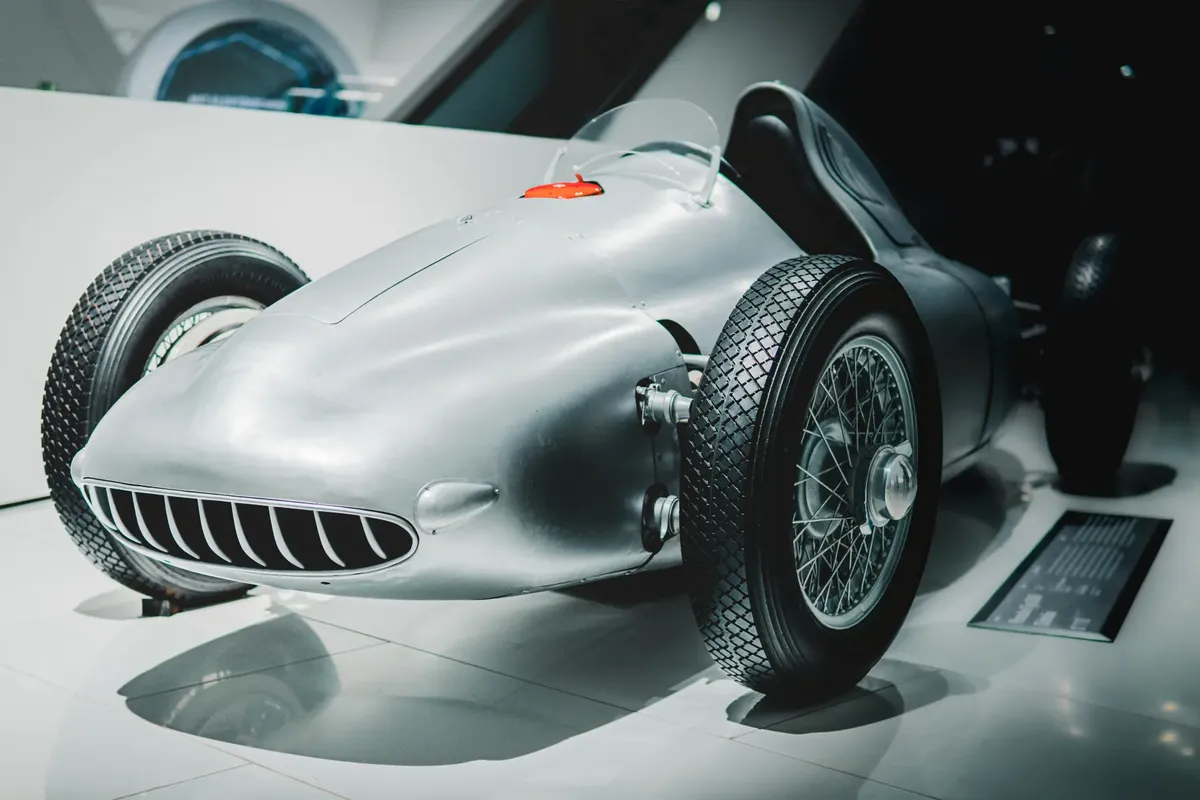 Vintage race car on display in a modern museum setting. Ideal for historical automotive concepts.